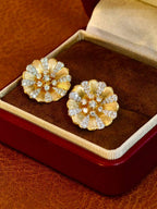 Close-up detail of brushed 18K gold flower stud earrings set with natural diamonds totaling 1.44 carats.