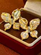 Close-up detail of brushed 18K yellow gold butterfly ear clips accented with 1.21 carats of natural diamonds.