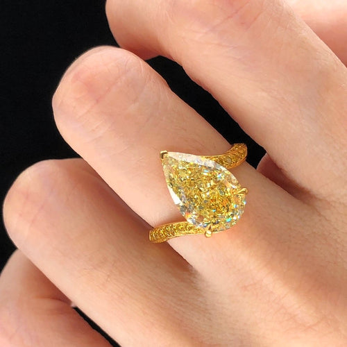  5.23 carat GIA fancy light yellow pear-shaped diamond engagement ring with side yellow diamonds.