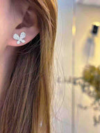 Close-up of a person wearing a silver butterfly earring with a blurred background