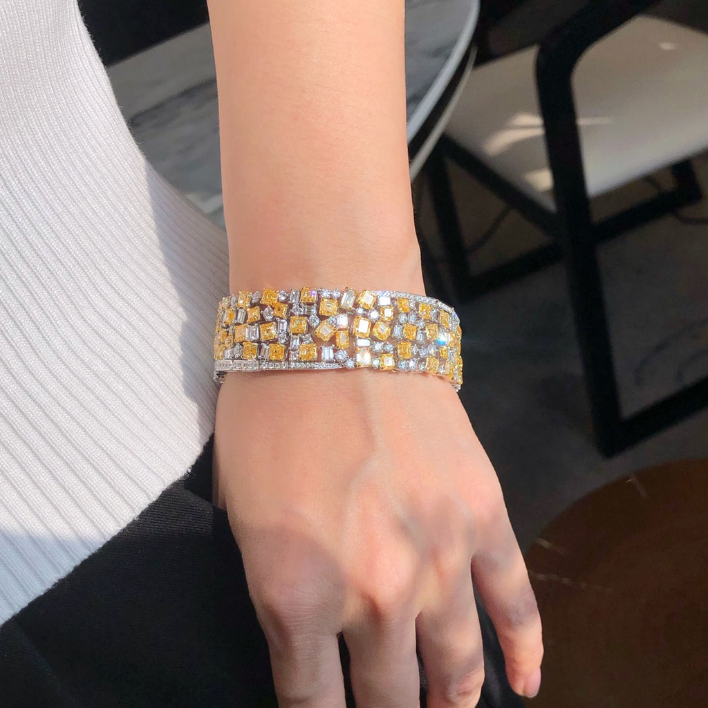 Close-up of fancy yellow and white diamonds in multi-shape 18k gold bracelet