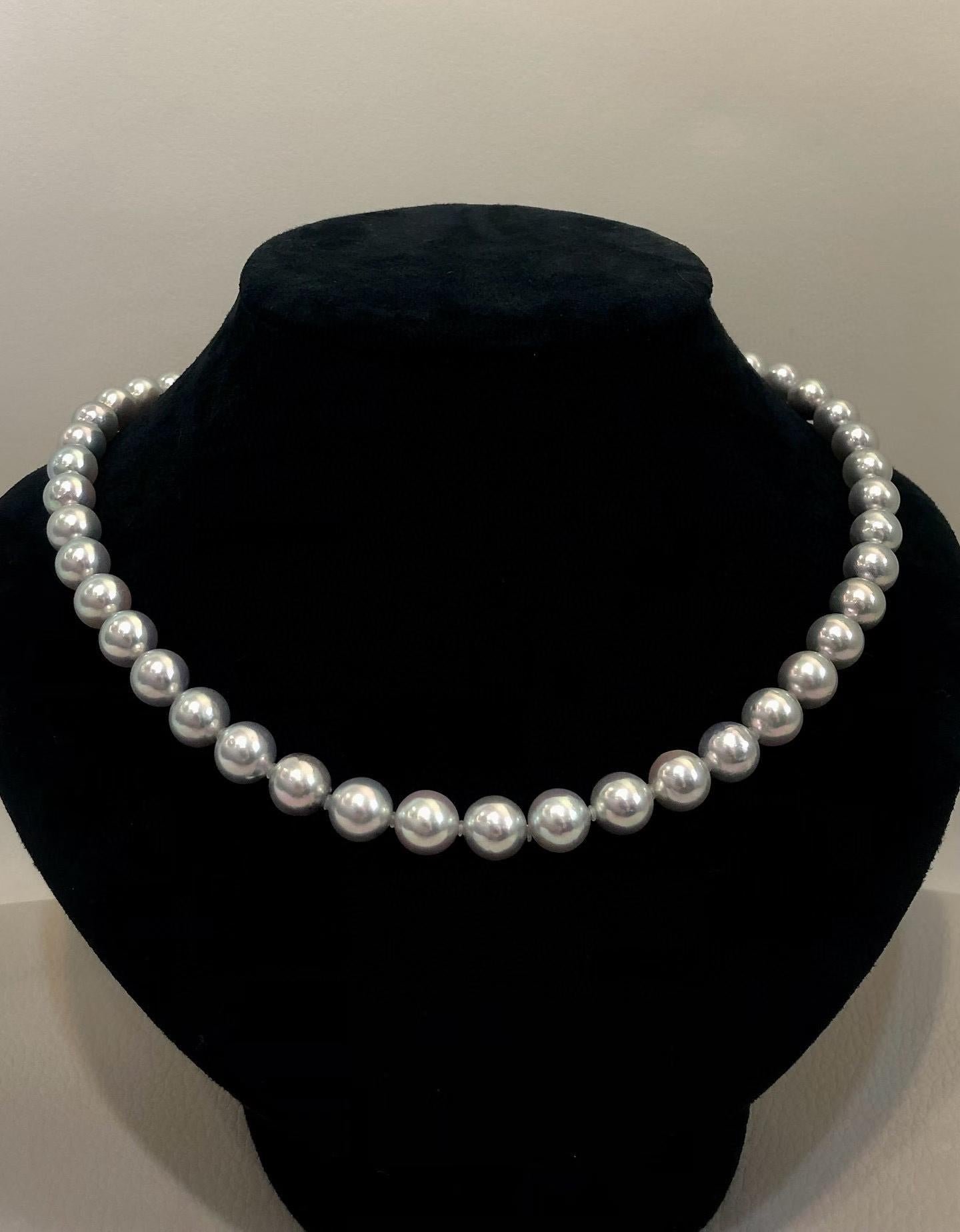 A classic strand of white freshwater pearls displayed on a black velvet jewelry bust against a neutral light gray background.