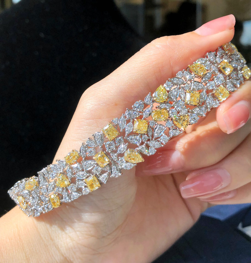  Model wearing fancy yellow and white diamond bracelet in an elegant setting.