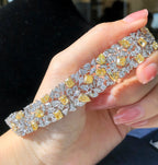  Model wearing fancy yellow and white diamond bracelet in an elegant setting.