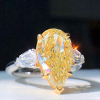  Model wearing luxury fancy yellow pear-shaped diamond ring, elegant and radiant design.