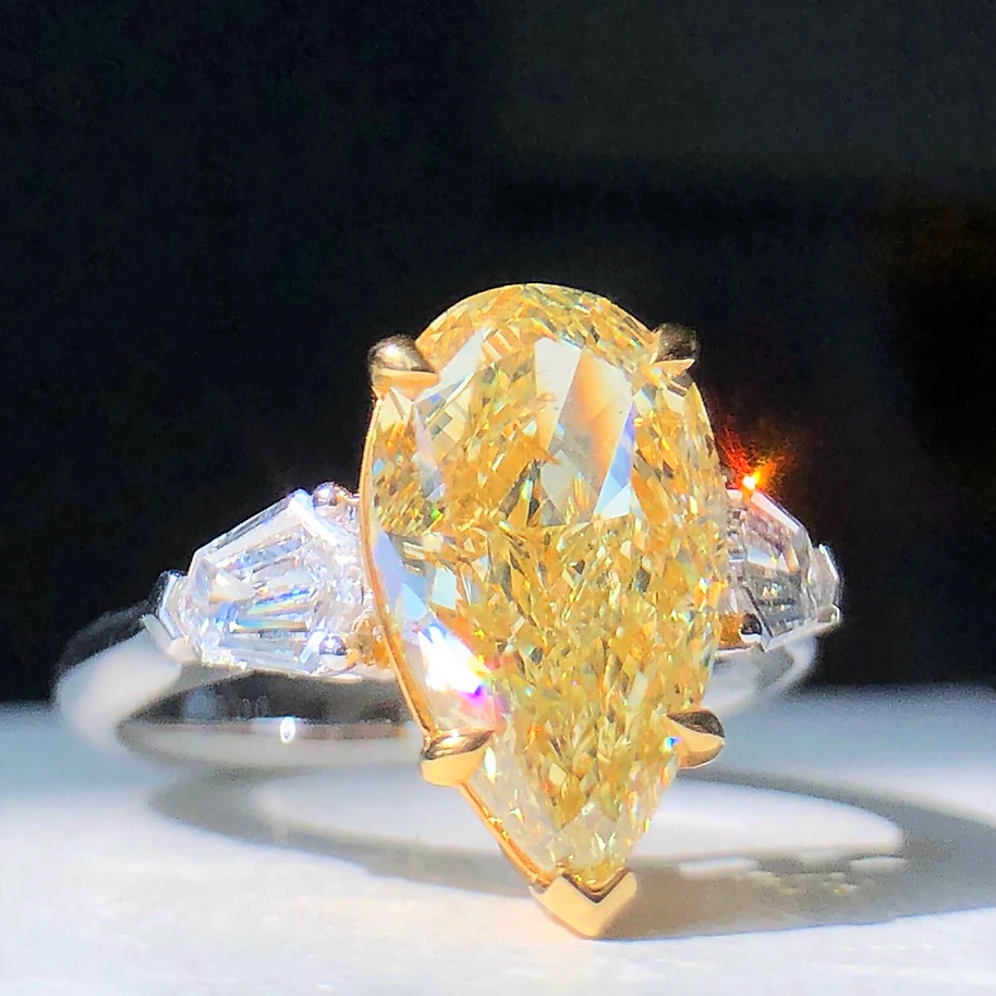  Model wearing luxury fancy yellow pear-shaped diamond ring, elegant and radiant design.